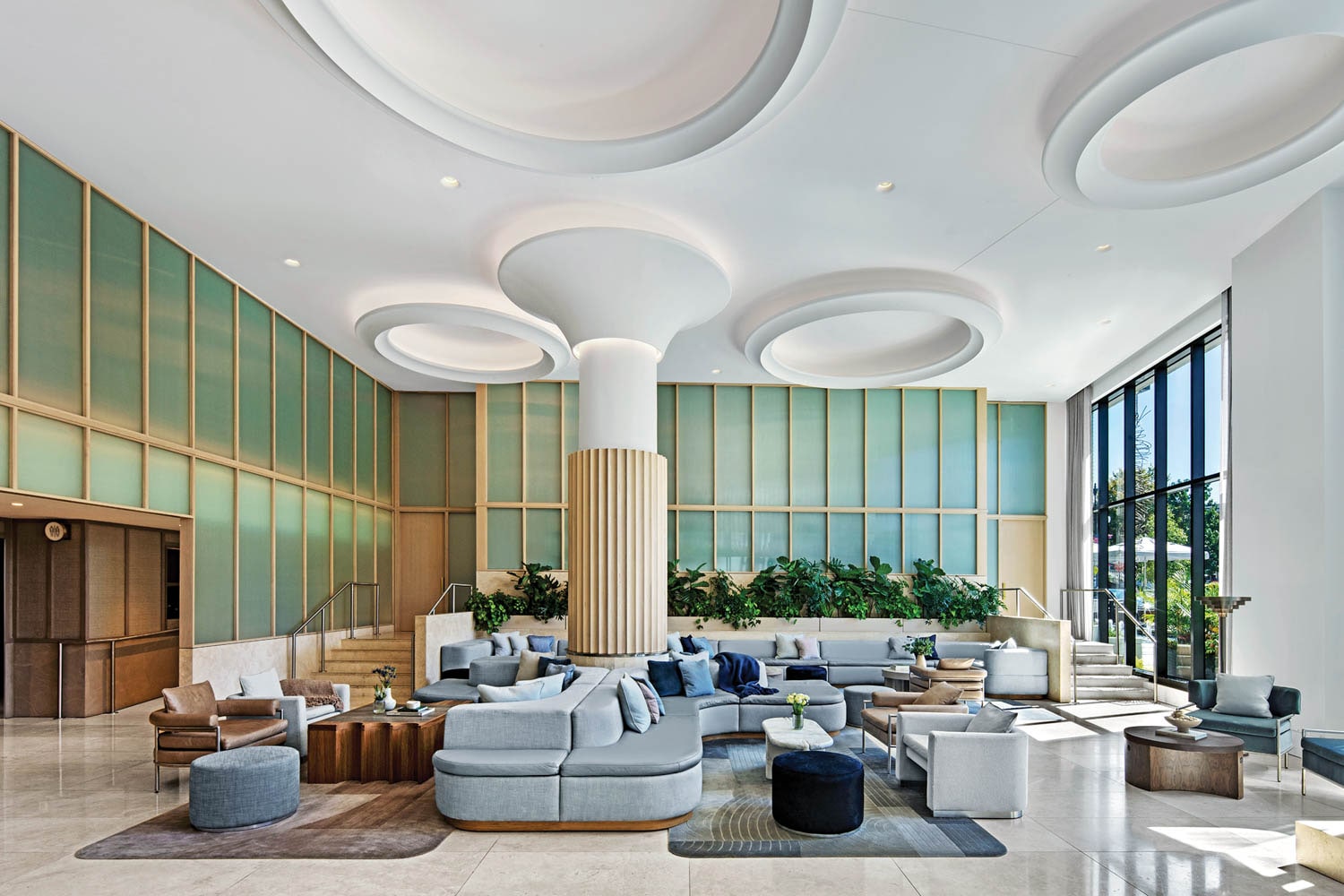 Light-filled lounge with curved seating, green wall panels and sculpted ceiling details