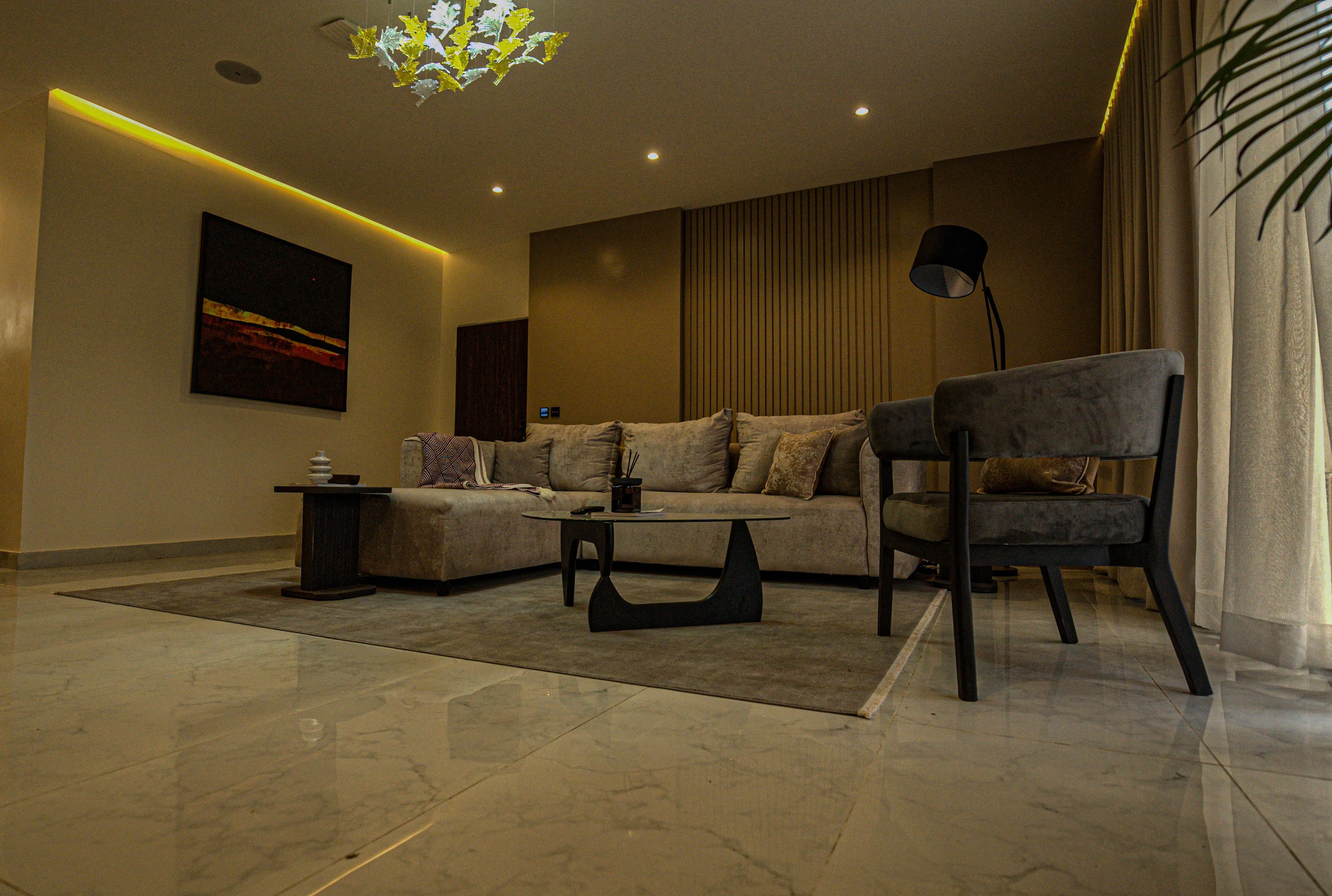 Wide living-room view with upholstered seating, reflective flooring and warm ceiling lighting